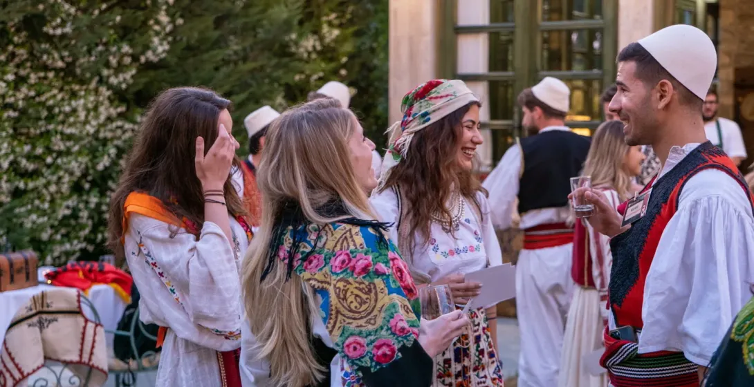Tourists enjoying an Albanian Night show, interacting with performers in traditional clothing.