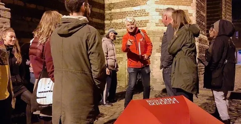 A guided tour group explores Bruges at night.