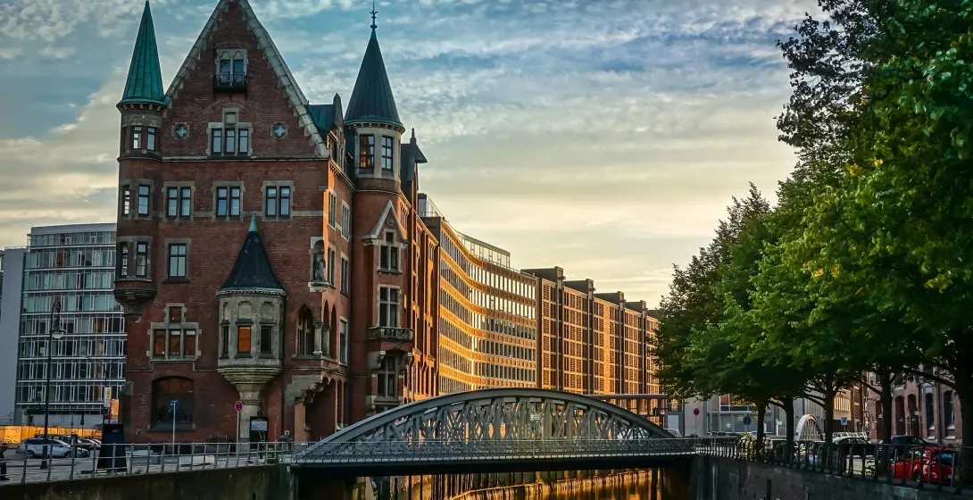 Sunset view of a charming canal in Hamburg, Germany, with a unique brick building and bridge.