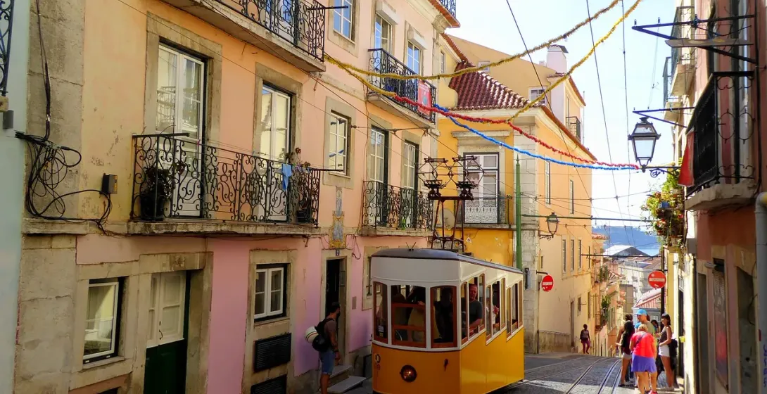A yellow tram climbs a hill in Lisbon's Alfama & Mouraria districts.