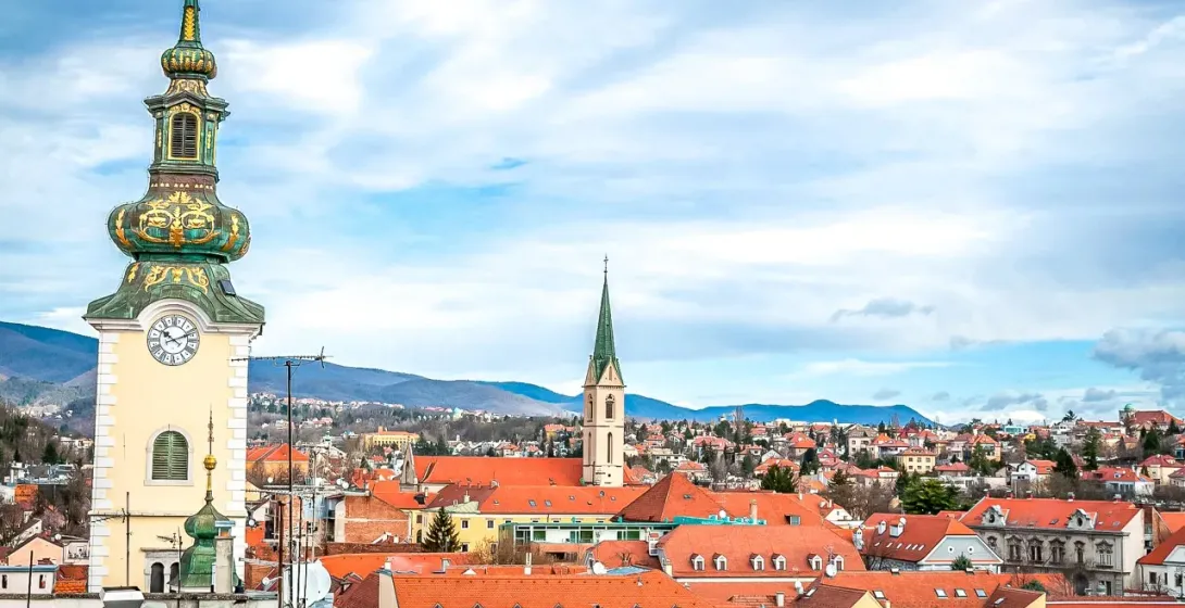 Panoramic view of Maribor, Slovenia, featuring a prominent clock tower and terracotta rooftops.