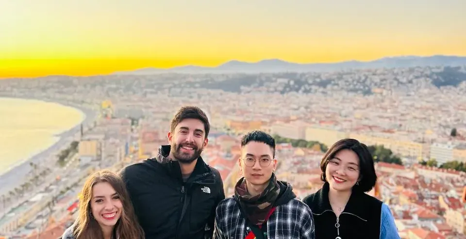 Happy tourists enjoying a stunning sunset view of Nice, France.