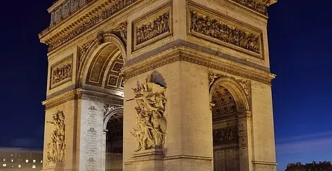 The Arc de Triomphe in Paris at night, illuminated beautifully.