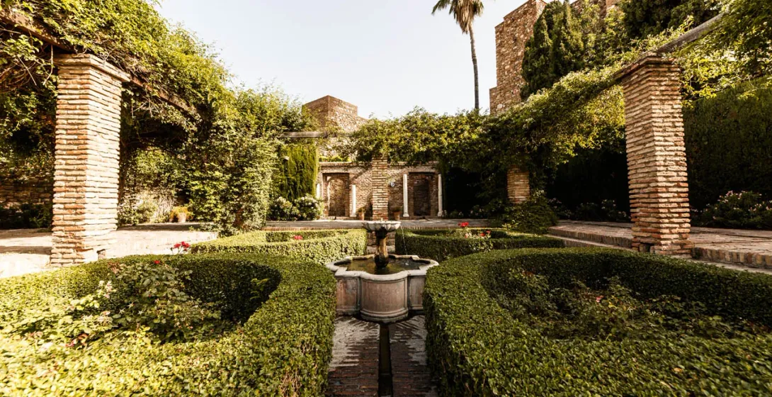 Serene courtyard in Seville, Spain, featuring a fountain and lush greenery.