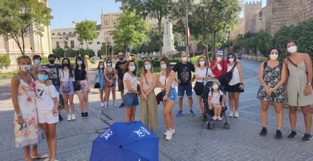 A guided tour group in Seville, Spain, poses for a photo near historic city walls.