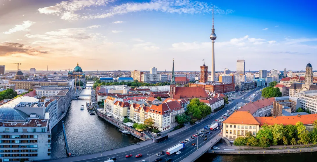 Panoramic view of Berlin's city center with the TV Tower, Berlin Cathedral, and the River Spree at sunset.