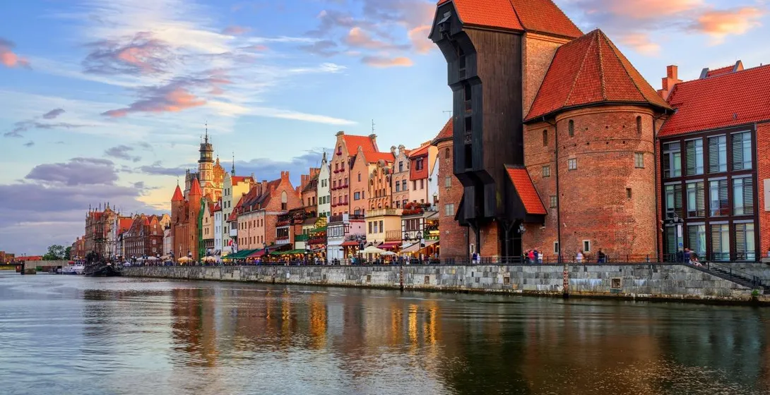 Historic waterfront of Gdansk with the medieval Crane (Żuraw) building, colorful houses, and reflections on the Motława River