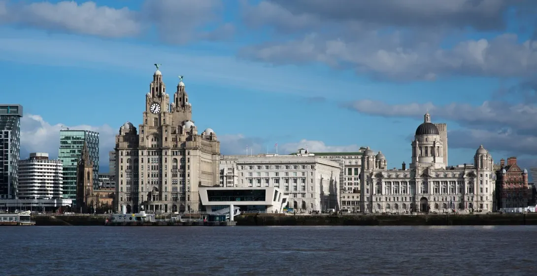 Liverpool waterfront with the Royal Liver Building, Cunard Building, and Port of Liverpool Building under a partly cloudy sky