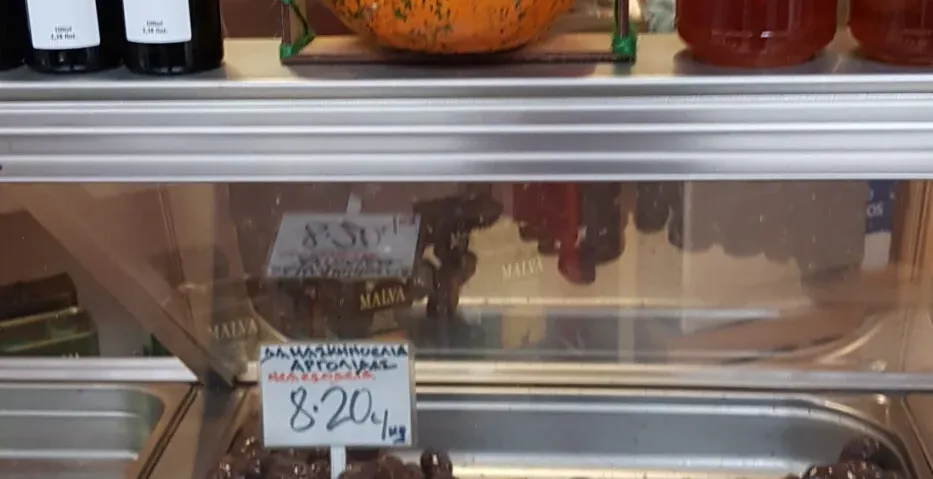 A colorful display of olives, honey, and olive oil at a Greek market.