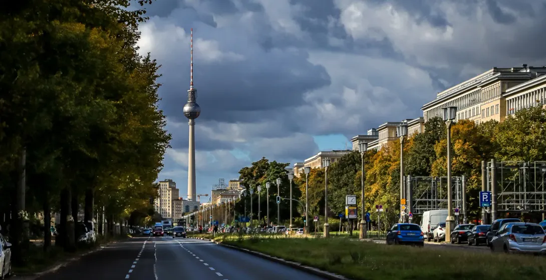 Berlin's iconic TV Tower viewed from a tree-lined avenue.