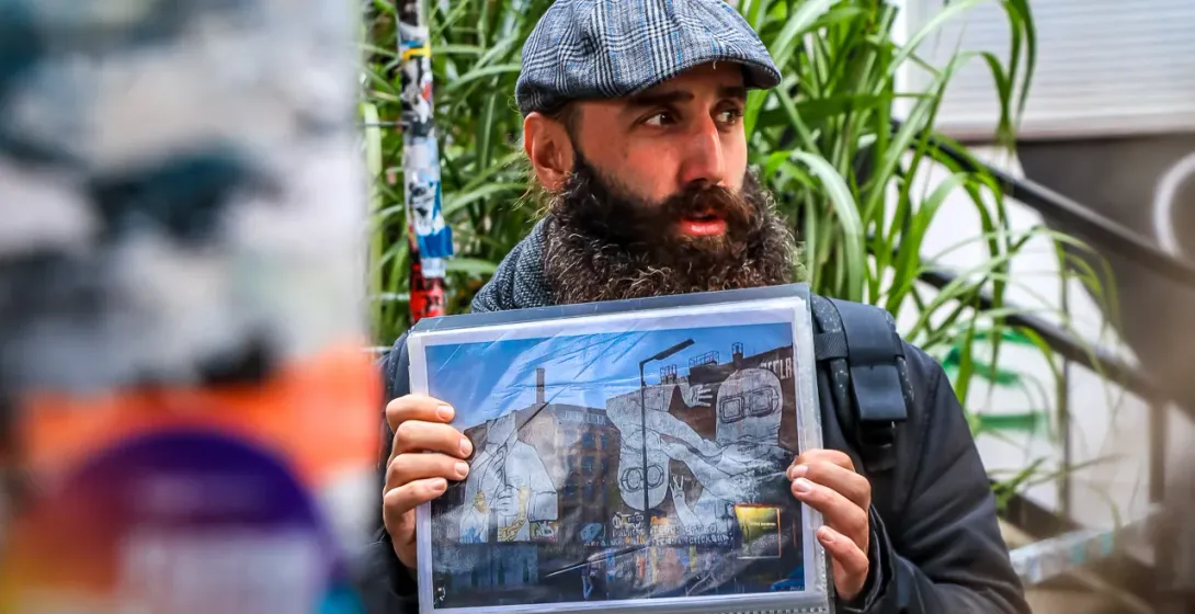 A tour guide in Berlin shows a photo of a vibrant street art mural.