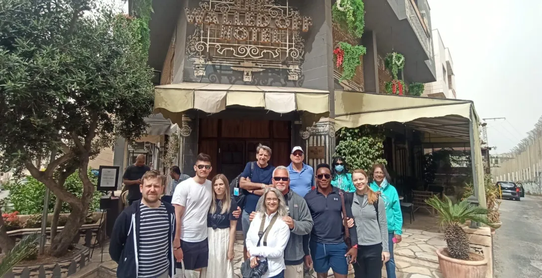 A happy tour group poses for a photo in front of The Walled Off Hotel in Bethlehem.