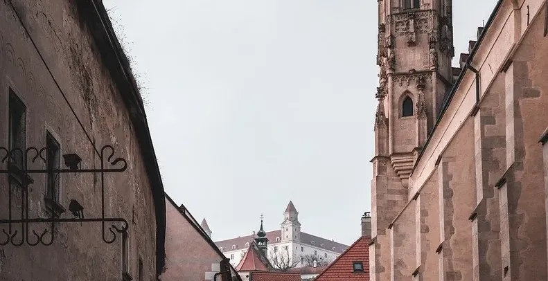 Cobblestone street in Bratislava's Old Town with Bratislava Castle in the background.