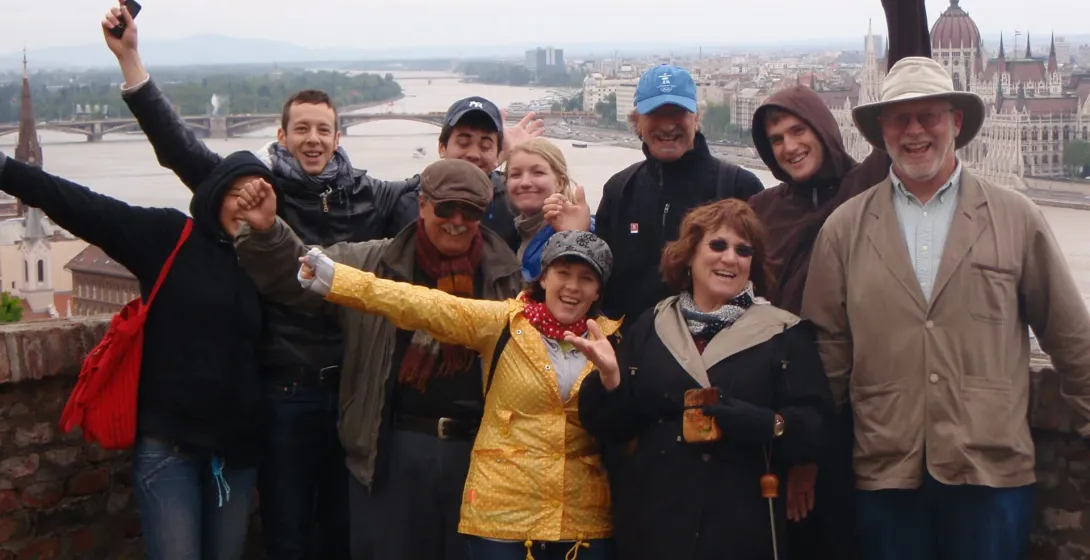 Happy tourists on a Budapest city tour, enjoying a panoramic view of the Parliament.