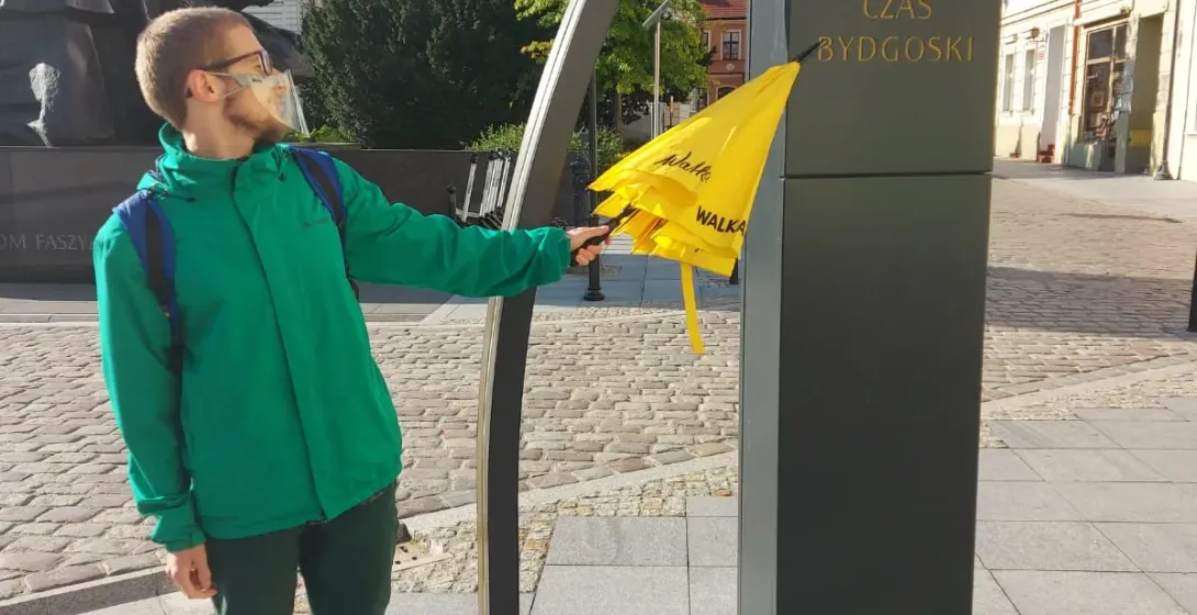 Tourist exploring a unique clock installation in Bydgoszcz, Poland.