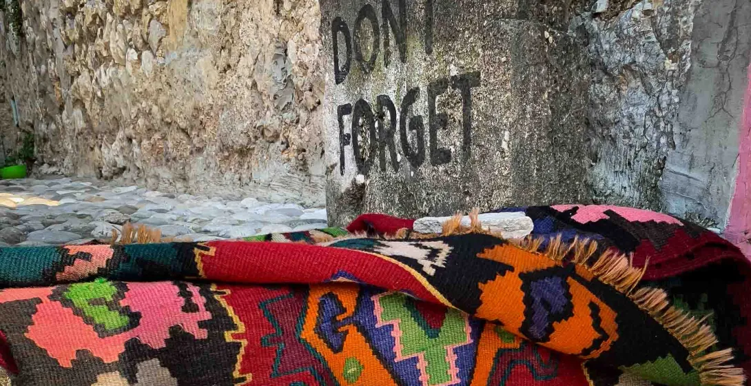 Colorful rug in Berat, Albania near a stone wall.