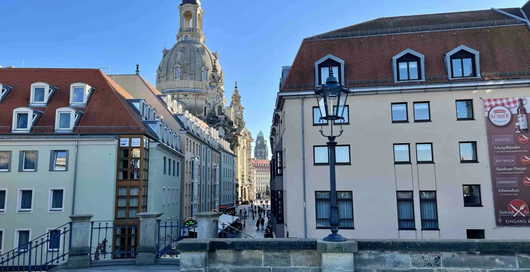A charming street in Dresden, Germany, with the Frauenkirche dome in the background.