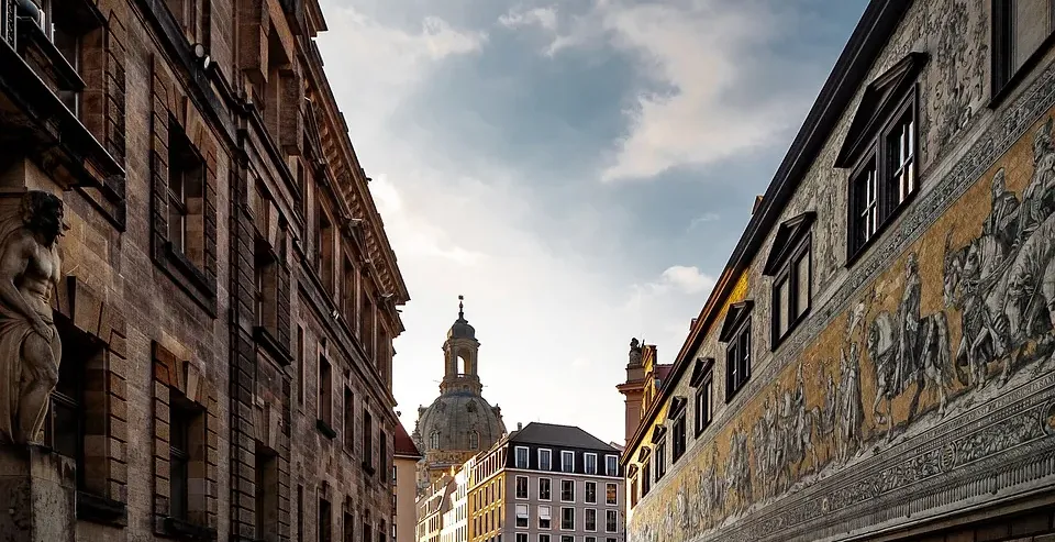 Cobblestone street in Dresden, Germany, with historic buildings and a fresco.