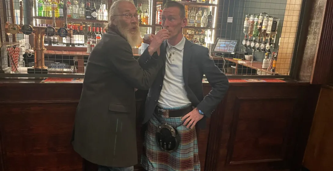 Two men enjoying drinks at a pub in Edinburgh, Scotland.