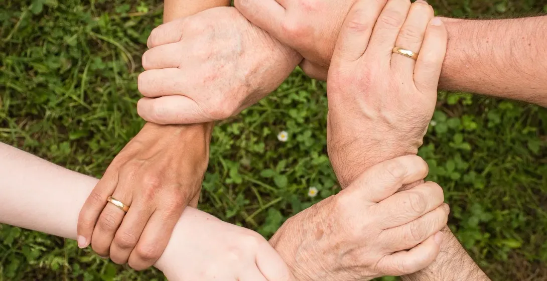 Hands clasped together in a circle, symbolizing unity and teamwork on a group tour in Gdansk.