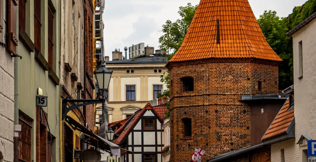 Charming cobblestone street in a historic German city, featuring a brick tower.