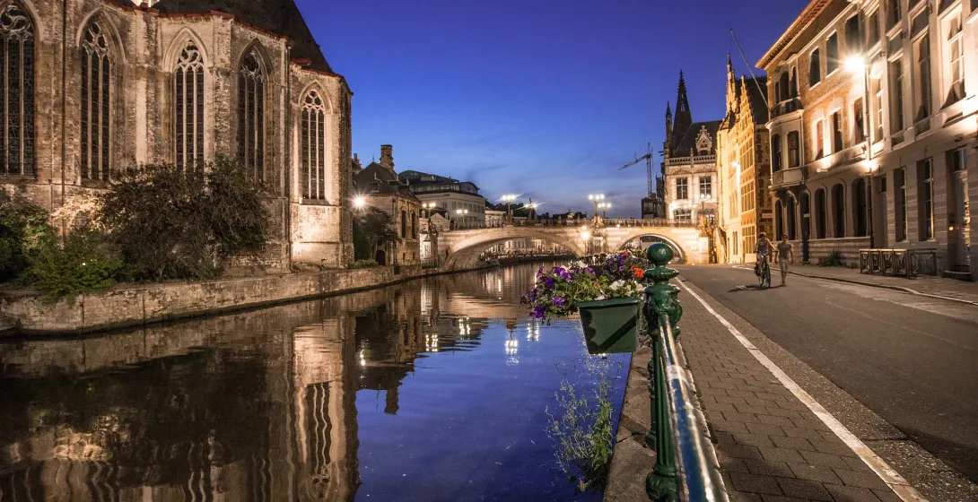 Ghent's charming canal at night, reflecting historic buildings.