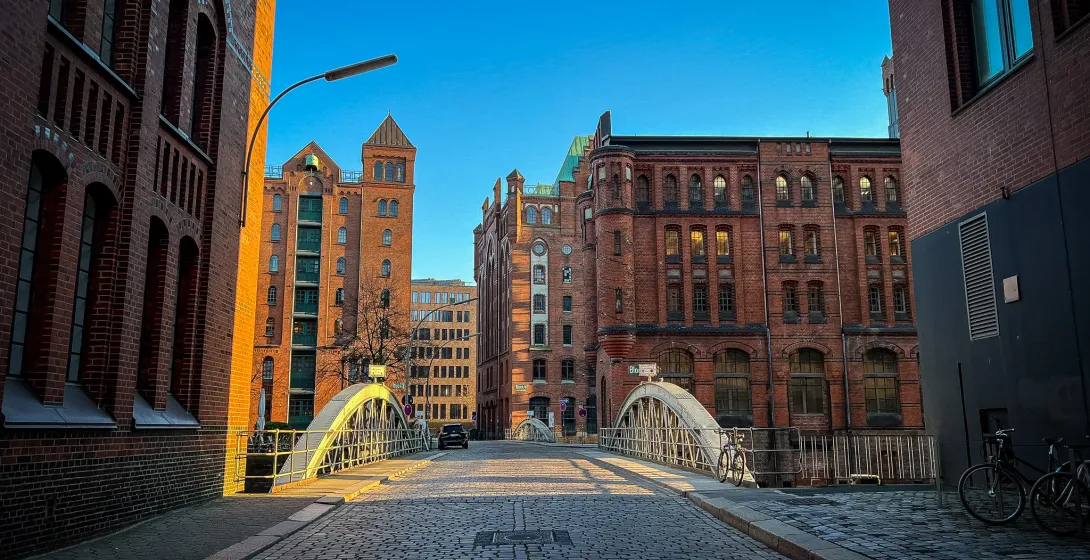 Cobblestone street in Hamburg, Germany, leading to a bridge with historic brick buildings.