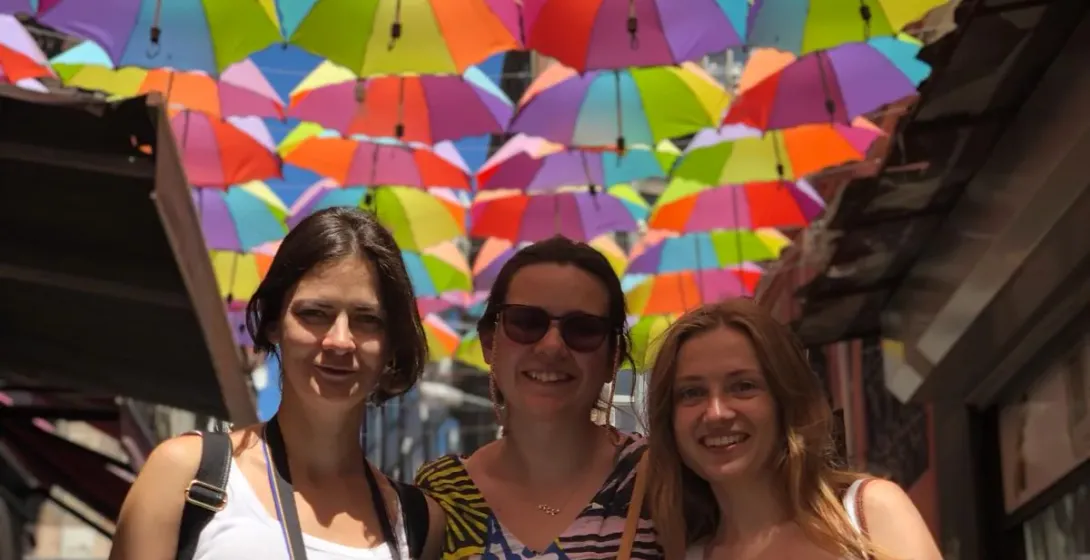 Happy tourists posing under a colorful umbrella street in Istanbul.