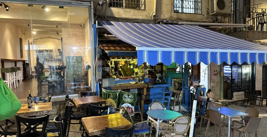 Outdoor seating area of The Parliament bar in Jerusalem at night.