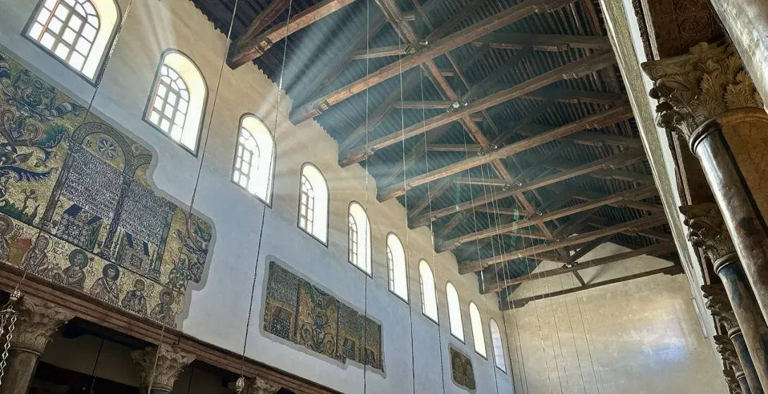 Sunbeams illuminate the majestic interior of a Jerusalem church, showcasing stunning mosaics and wooden beams.
