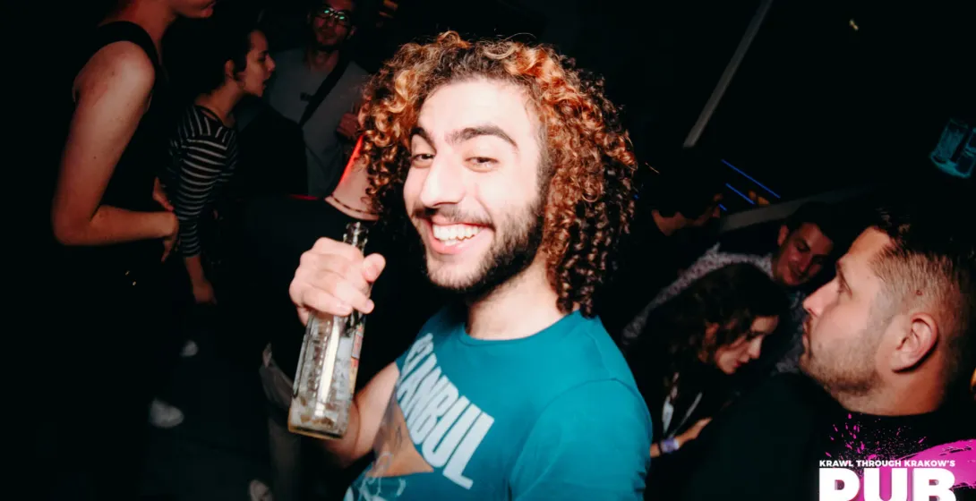 A smiling man enjoys a pub crawl in Krakow, Poland.