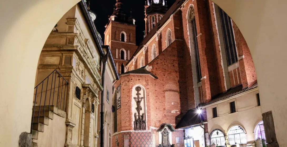 St. Mary's Basilica in Krakow at night, viewed through an archway.