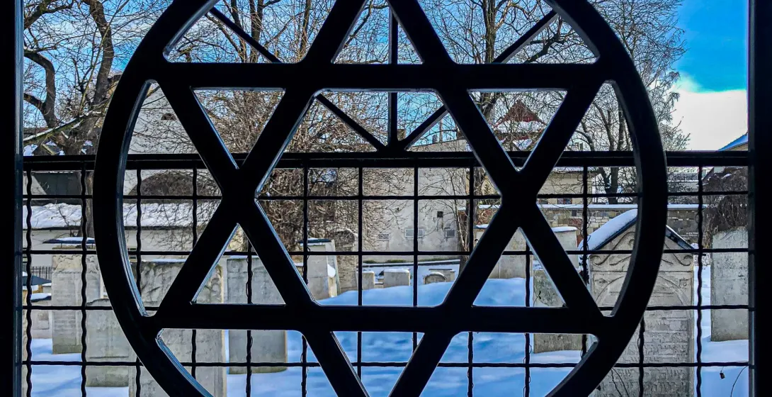 Star of David gate overlooking a snow-covered Jewish cemetery in Krakow, Poland.