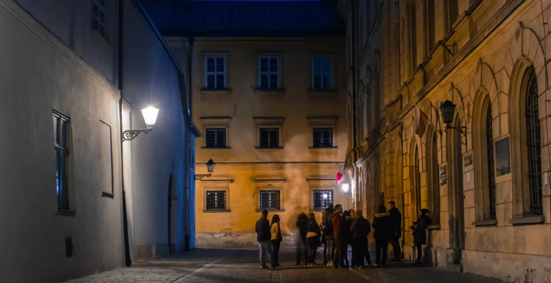 A guided tour group explores the charming, historic streets of Krakow at night.