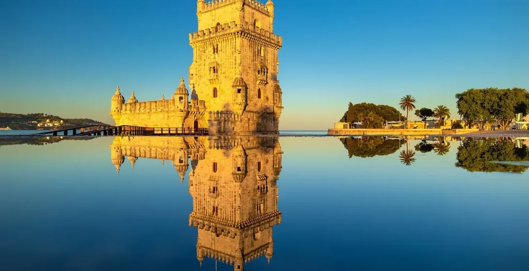 Belém Tower in Lisbon, Portugal, reflected in the water at sunrise.
