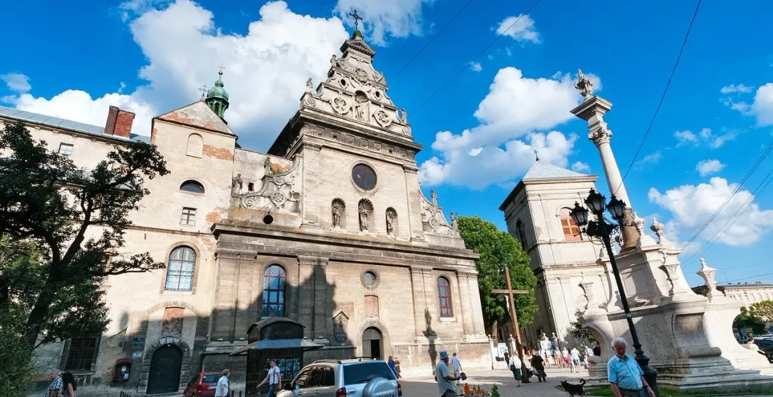 Tourists exploring the historic Church of St. Anne and Plague Column in Lviv, Ukraine.