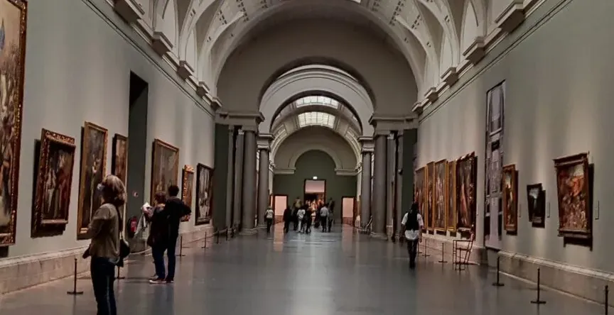 Grand hallway in an art museum with paintings and visitors.