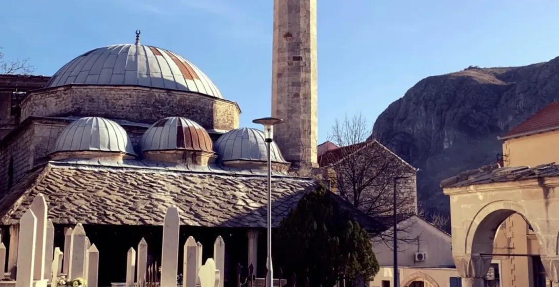 A serene mosque in Montenegro with a tall minaret and a peaceful graveyard.