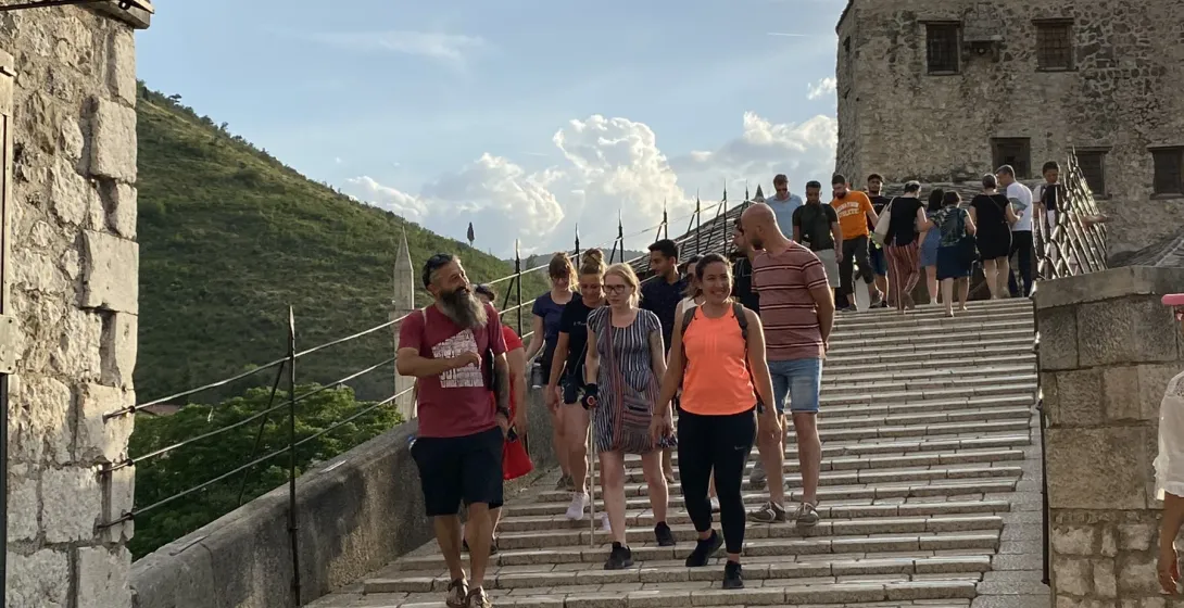 Guided tour group walking across the historic Stari Most bridge in Mostar.