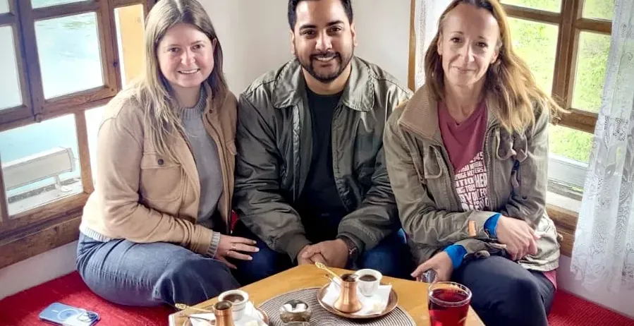 Three tourists enjoy traditional coffee with a river view in Mostar.
