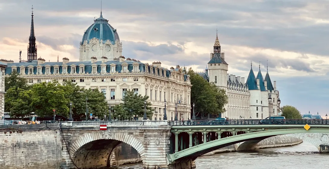 A picturesque bridge in Paris, France, with the Conciergerie and other historical buildings in the background.