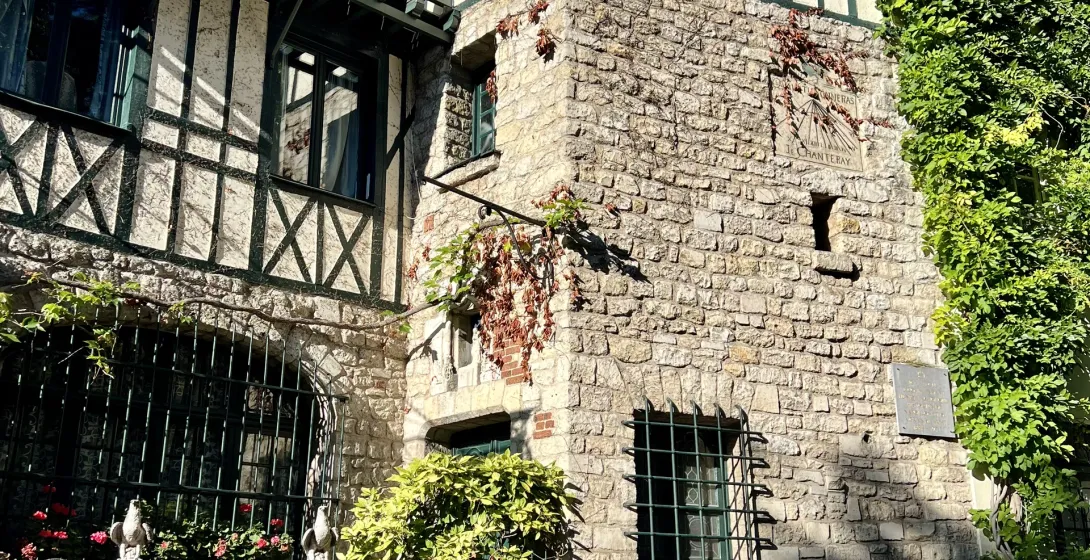 A charming historic building in Paris, showcasing a mix of architectural styles and lush greenery.