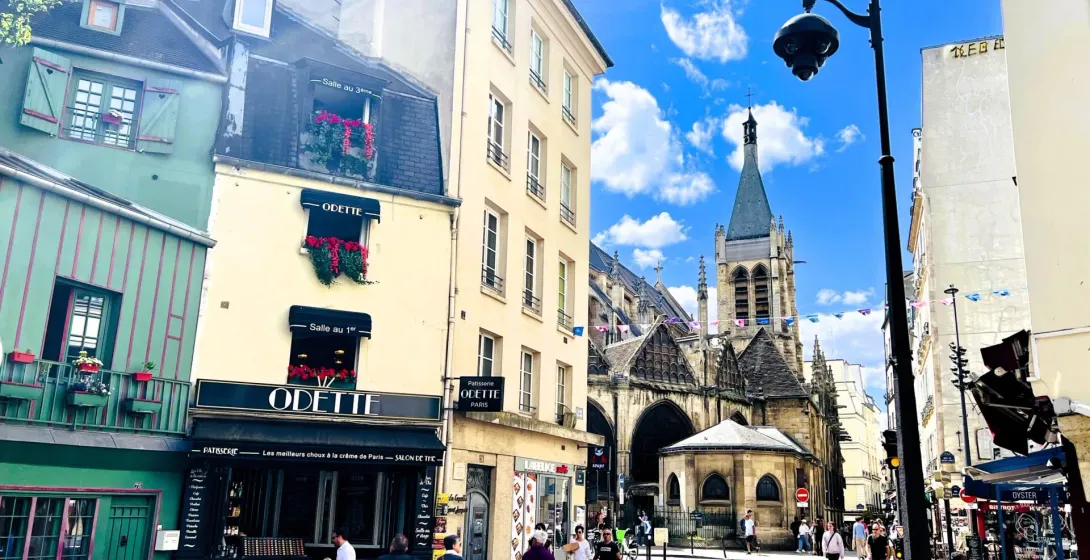 Sunny Parisian street scene with a charming cafe and historic church.