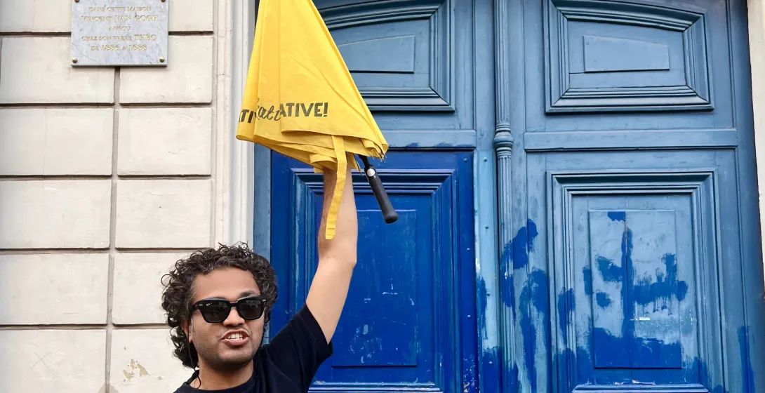 A tour guide in Paris holds up a yellow umbrella outside a building where Vincent van Gogh once lived.