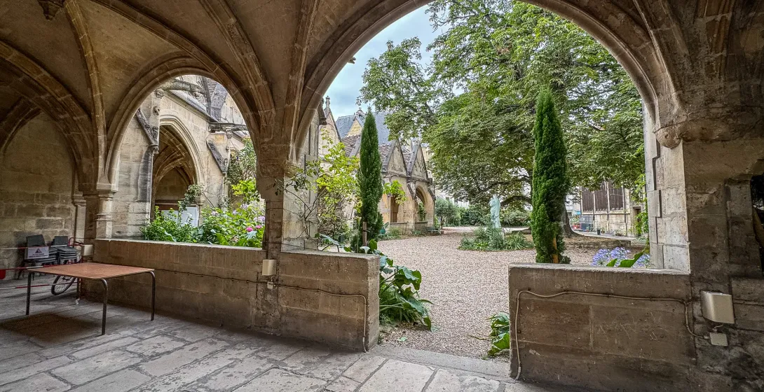 Serene courtyard in Paris, seen through ancient stone arches.