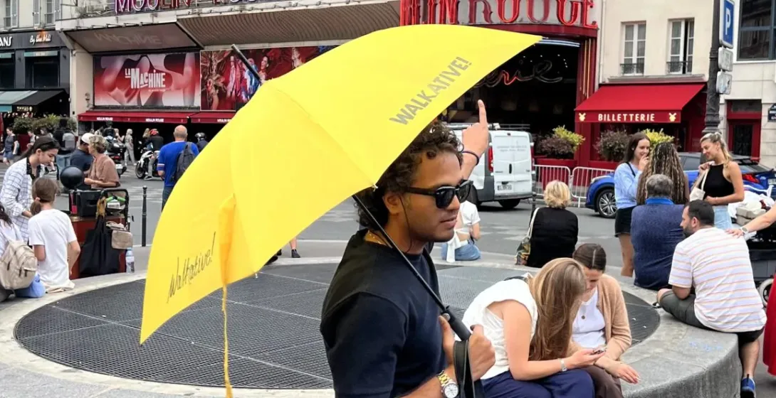 A tour guide in Paris points towards the Moulin Rouge.