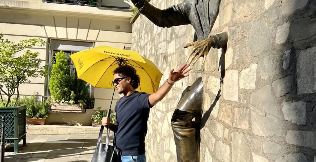 A tour guide in Paris interacts with a unique bronze sculpture.