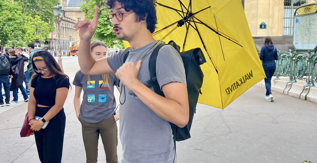 A tour guide leads a small group on a walking tour in Paris, France, near the Sainte-Chapelle.