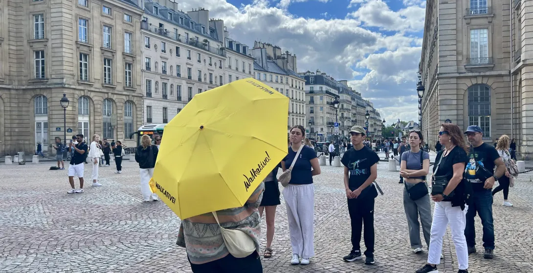 A Walkative! walking tour guide leads a group through a Parisian square.