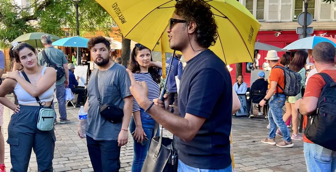 A tour guide leads a small group on a walking tour in Paris.